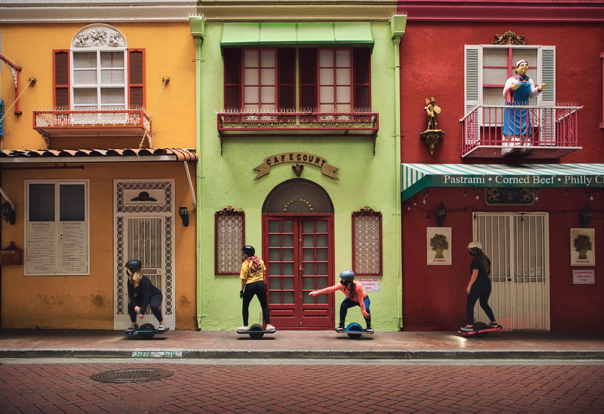 4 girls riding onewheels infront of buildings