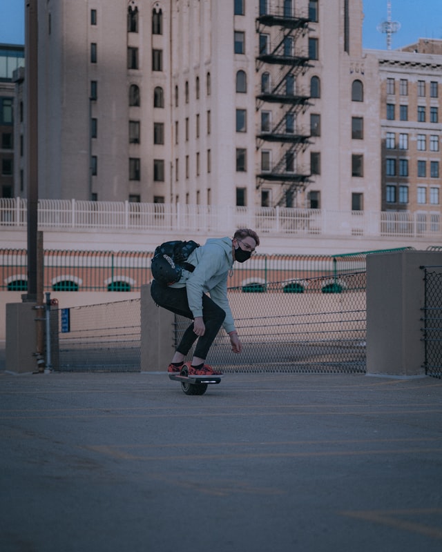 Guy ridding onwheel pint with building in background
