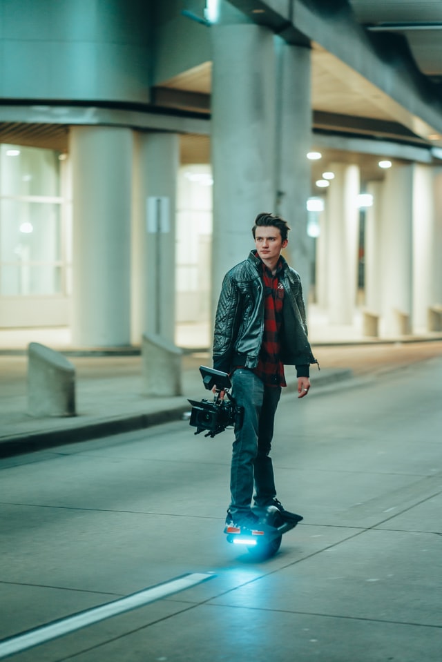 Guy riding onewheel holding a camera in tunnel