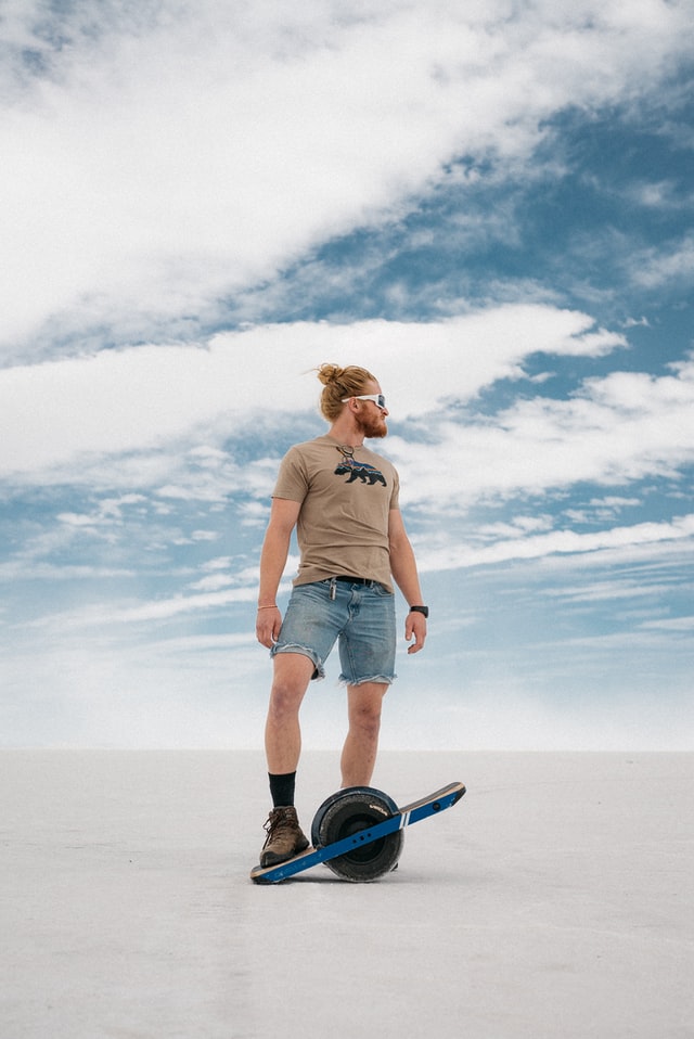 guy posing with onewheel on a beach